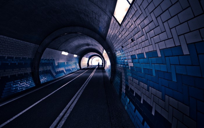 People walking in a tiled tunnel