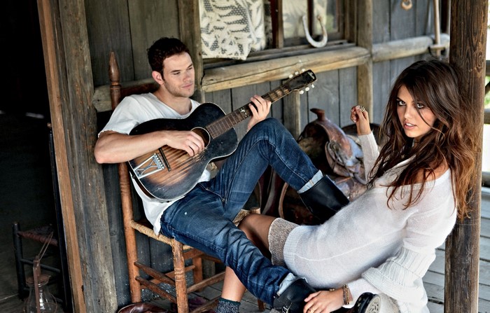 Kellan Lutz plays guitar with a woman by a saddle