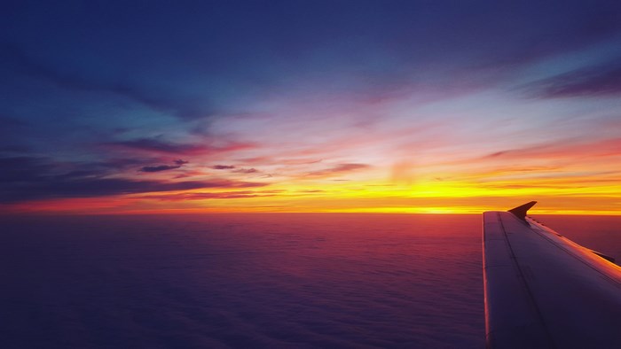 Airplane wing against a colorful sunset sky