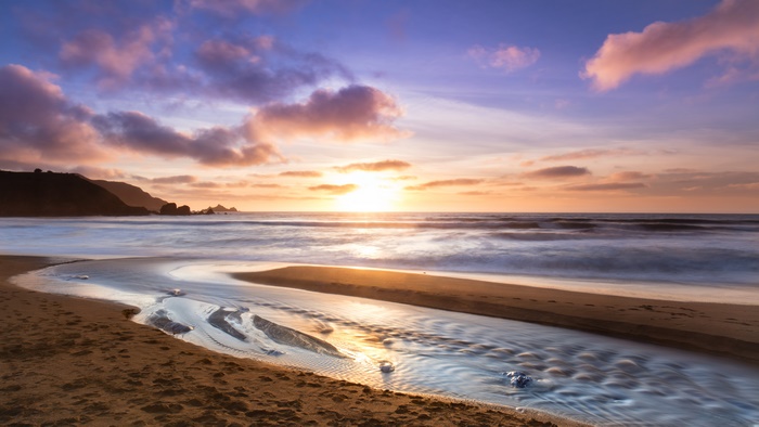 Sunset over ocean waves and beach stream