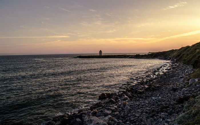 Coastal landscape with lighthouse at sunset