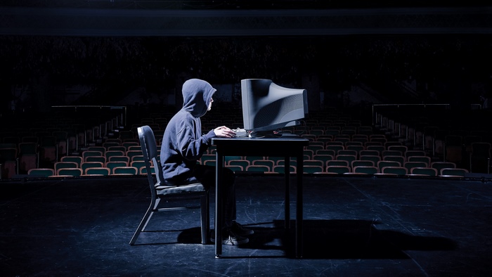 Person in hoodie using computer in theater