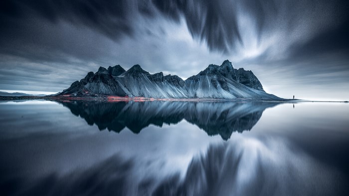 Mountain range reflected in water with person