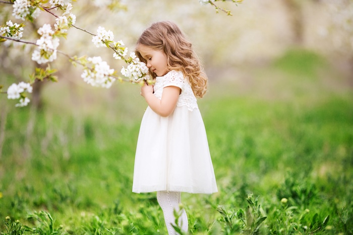 Little girl smelling flowers in a garden