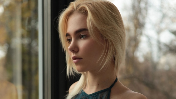 Thoughtful Blonde Woman with Short Hair by Window