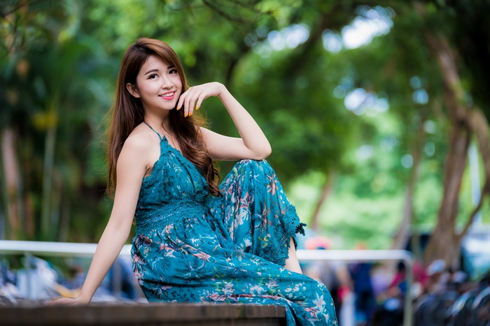 Asian woman in a blue floral dress sitting outdoors