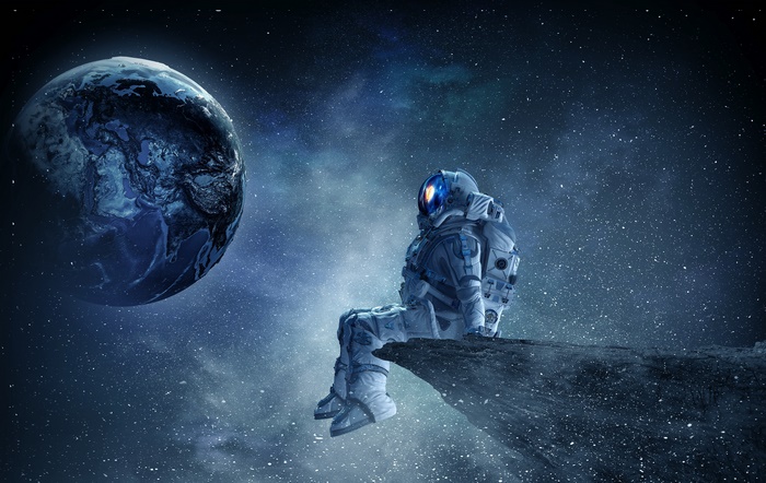 Astronaut sitting on a rock looking at Earth in space