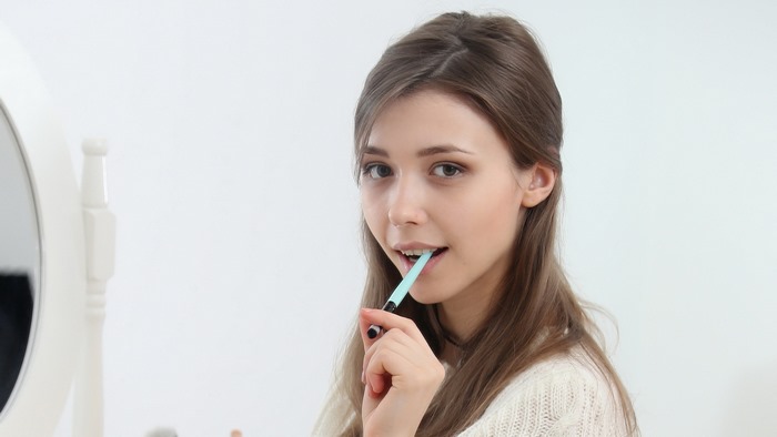 Mila Azul Holding Makeup Brush Near Face