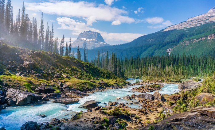 Turquoise river flowing through a rocky forest landscape with mountains