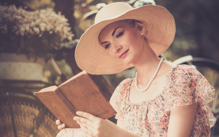 Woman in a wide-brimmed hat reading a book