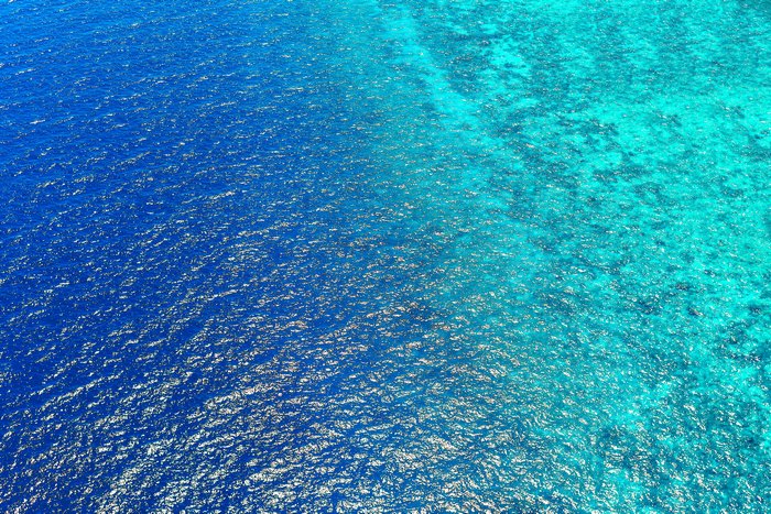Aerial view of ocean water transitioning from deep blue to turquoise