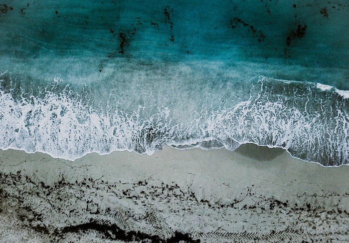 Aerial view of ocean waves crashing on a sandy beach