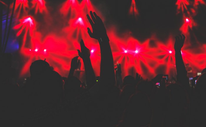 Crowd with hands up at a concert with red lights