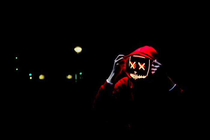 Person in a red hoodie wearing a glowing mask at night