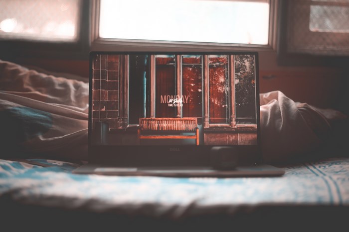 Dell laptop on a bed with windows in background