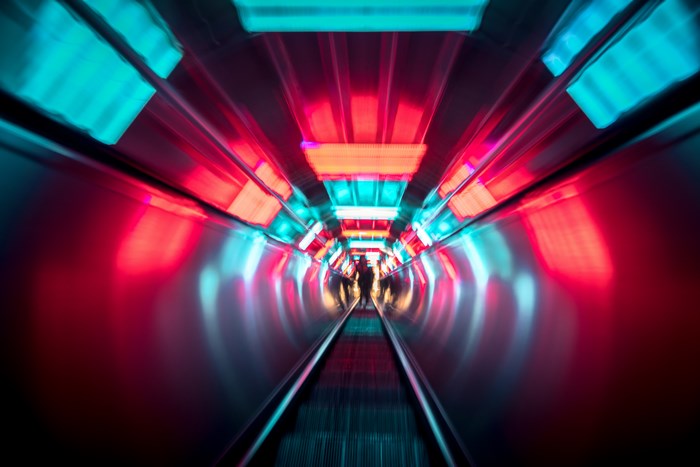 People on a moving walkway with neon lights