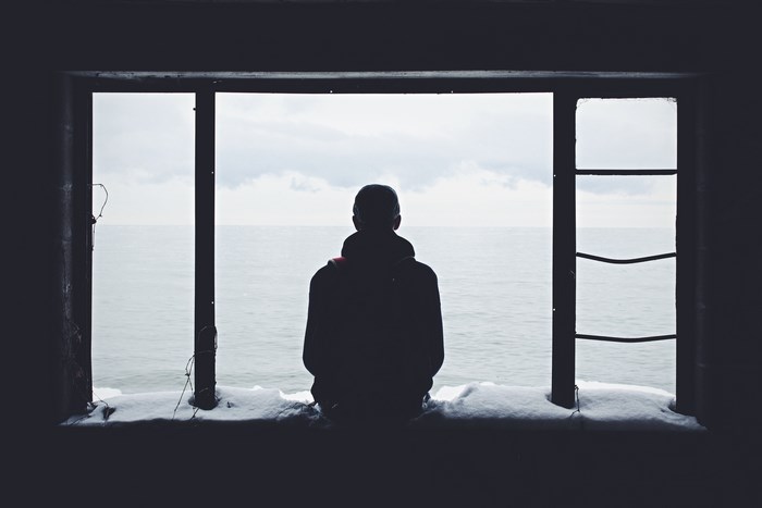 Person looking out a window at the sea in winter