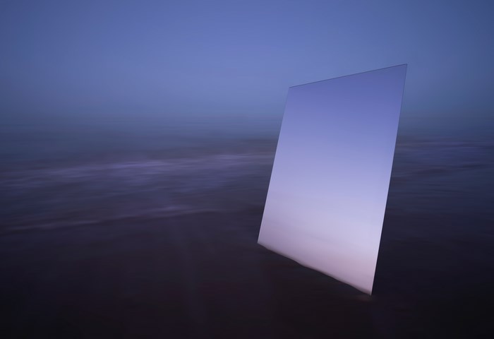 Mirror reflecting gradient sky on a beach at dusk