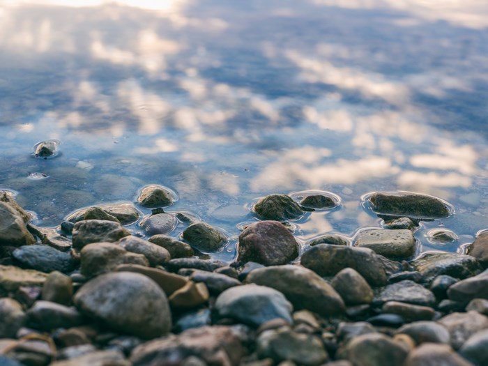 Pebbles on the Shoreline with Water Reflection