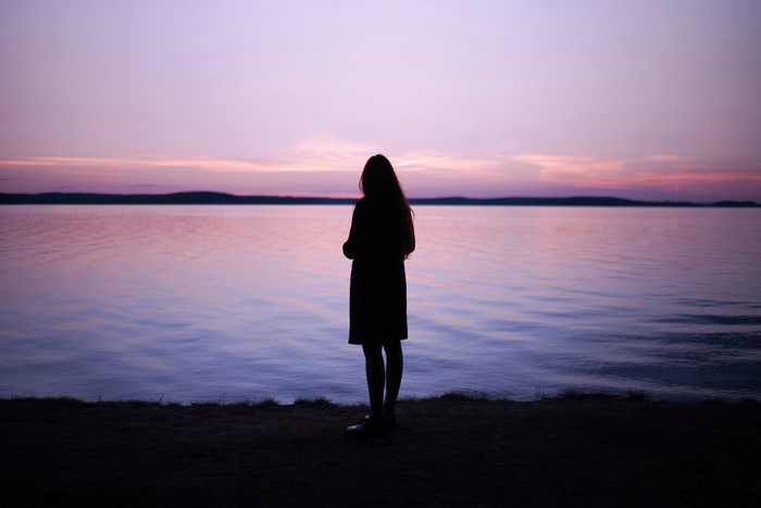 Woman silhouetted at dusk by a lake