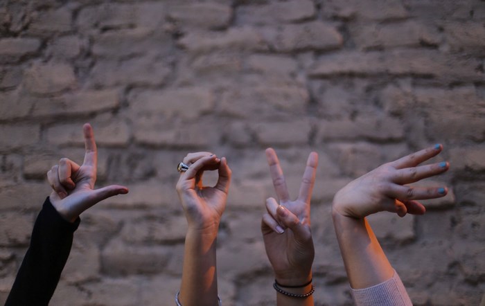 Hands forming the word LOVE against a brick wall