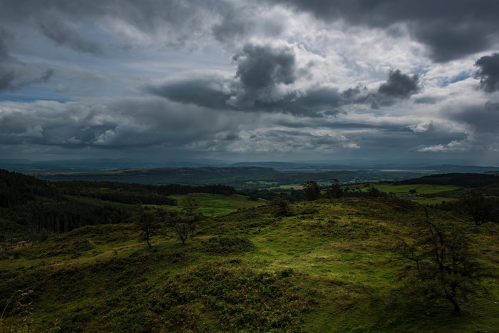 Moody landscape with dark clouds over rolling green hills