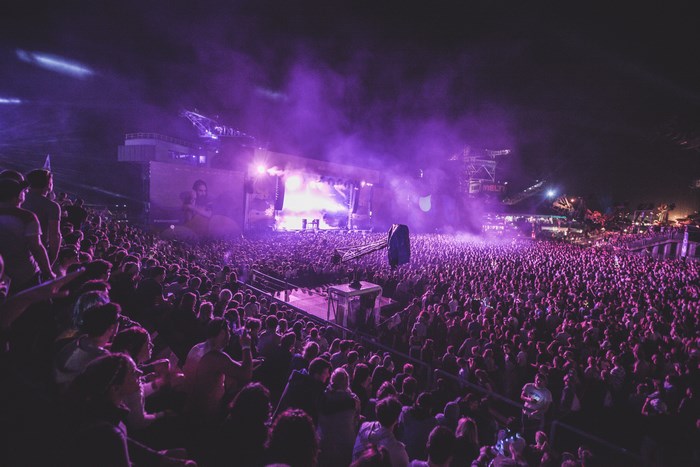 Crowd at a concert with purple smoke and stage lights