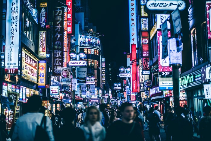 Shibuya street at night with neon signs and crowds
