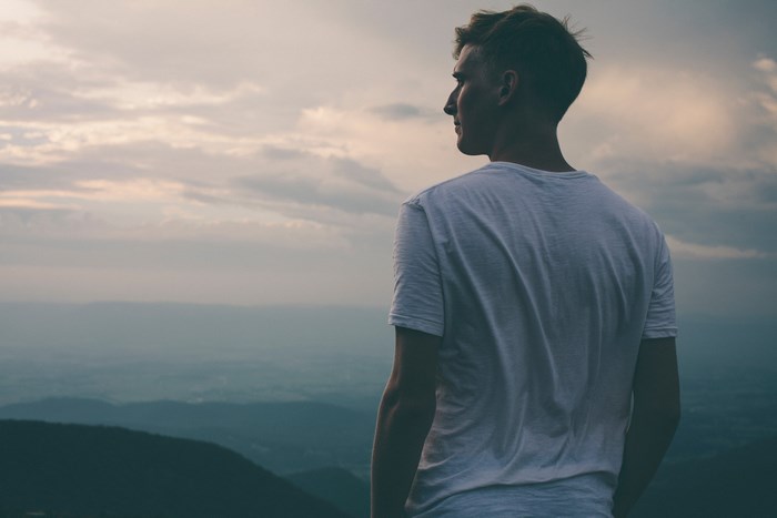 Man in t-shirt looking at mountains at sunset