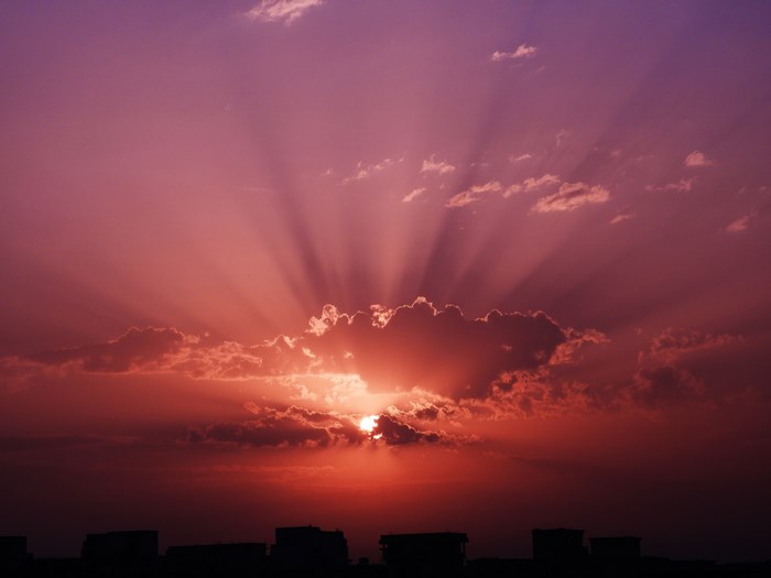 Sunset with crepuscular rays over city skyline