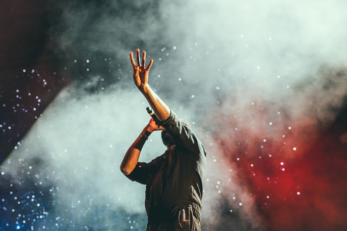 Singer performing on stage with microphone and smoke