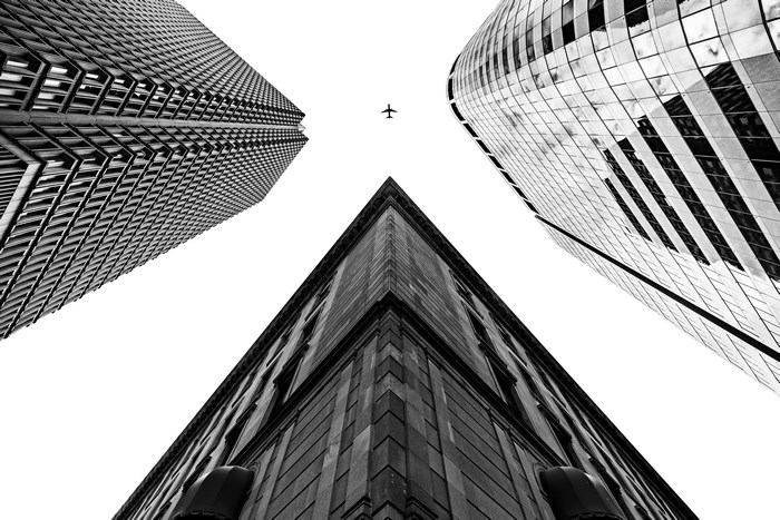 Looking up at skyscrapers with a plane in the sky