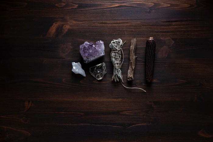 Crystals, sage, and corn on a dark wooden table