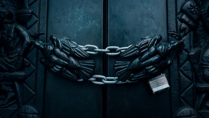 Dark double doors locked with a chain and padlock
