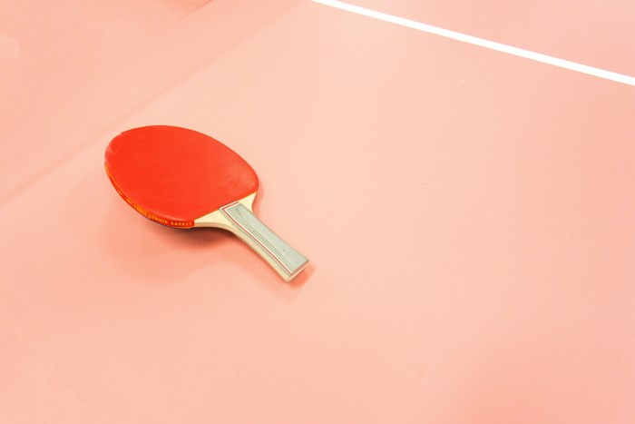 Red ping pong paddle on a pink table
