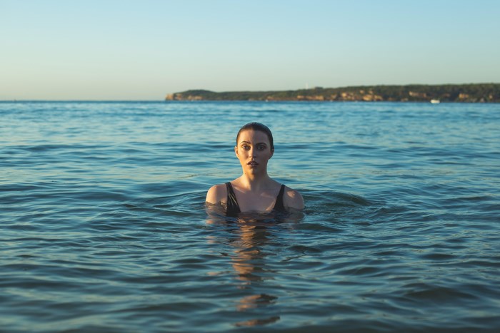 Woman swimming in the ocean at golden hour