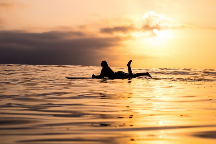 Silhouette of a surfer on a surfboard at sunset