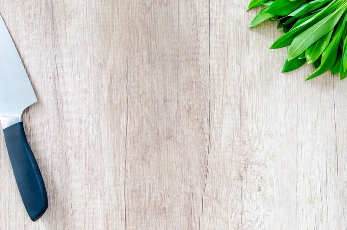 Knife and fresh basil on wooden cutting board