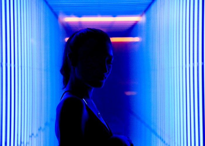 Silhouette of a woman in a blue light installation