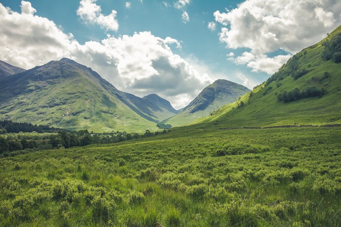 Green valley with mountains and clouds