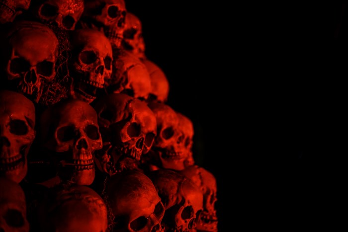 Red-lit Pile of Human Skulls in Darkness