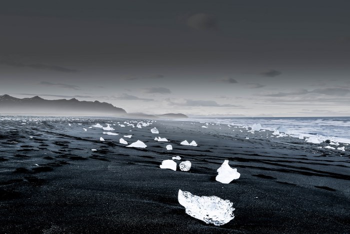 Black sand beach with icebergs and mountains