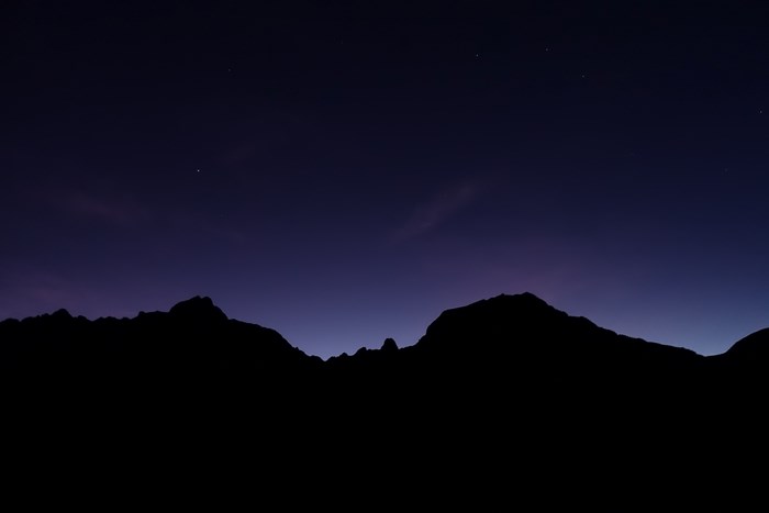 Silhouette of mountains against a starry night sky