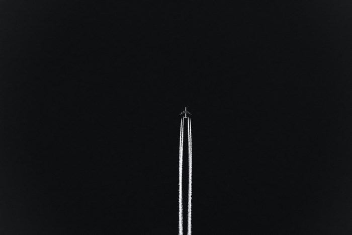 Airplane flying at night with contrails