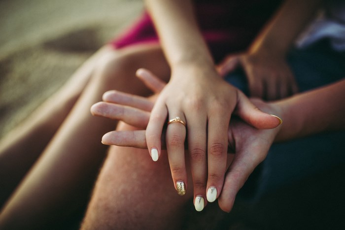 Couple holding hands with engagement ring