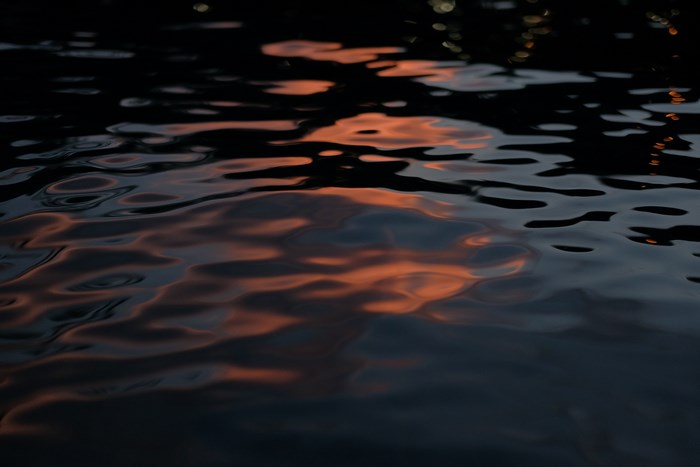 Sunset reflection on dark rippling water