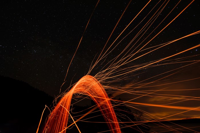 Light painting with sparks under a starry sky