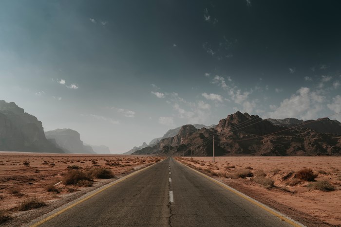 Desert road with mountains and sky