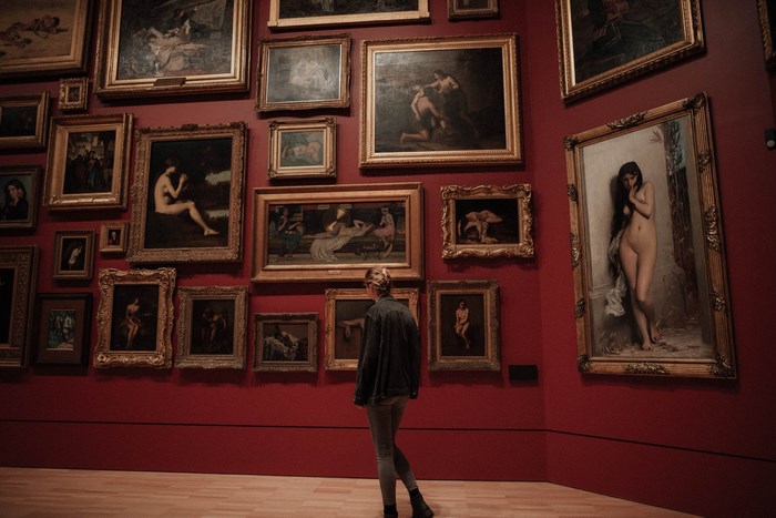 Woman Viewing Classic Nude Paintings in Red Gallery