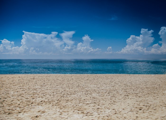 Sandy beach with blue ocean and cloudy sky